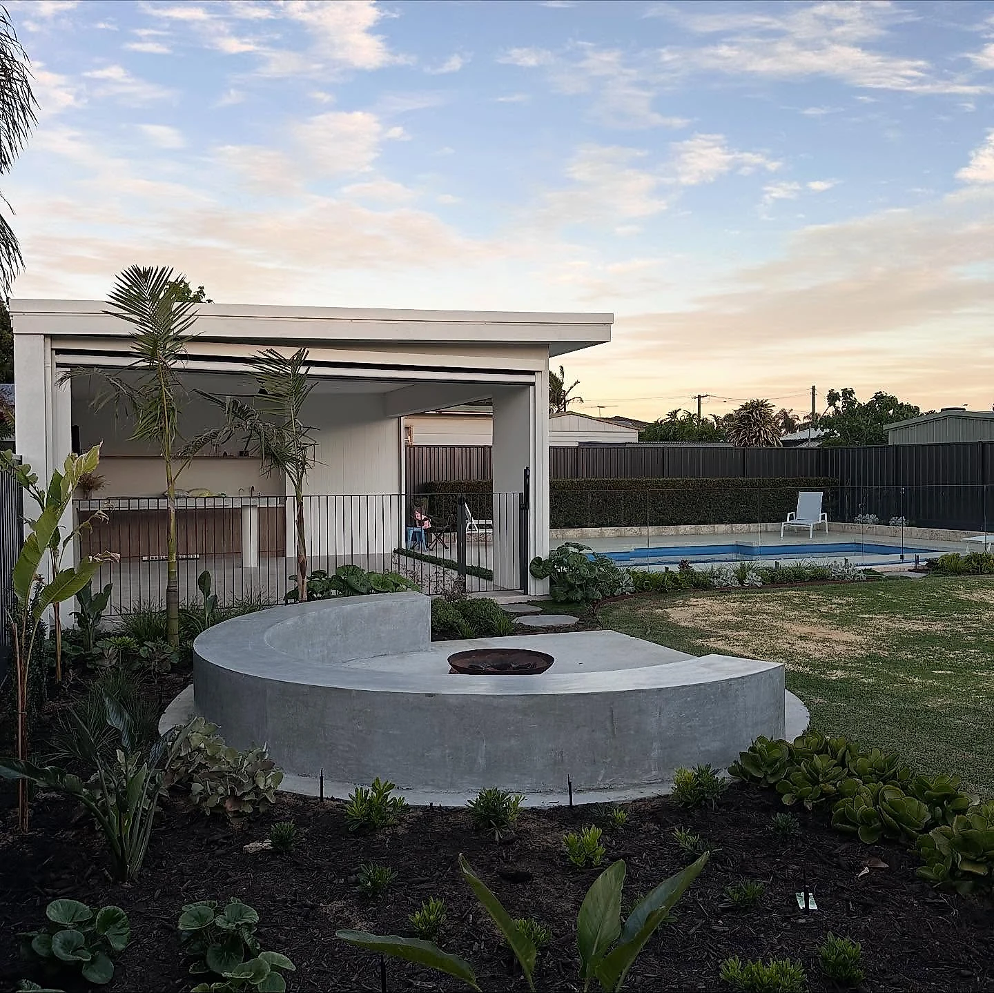A run of architectural pieces finishing a backyard, poured to sit with the landscaping rather than as a single