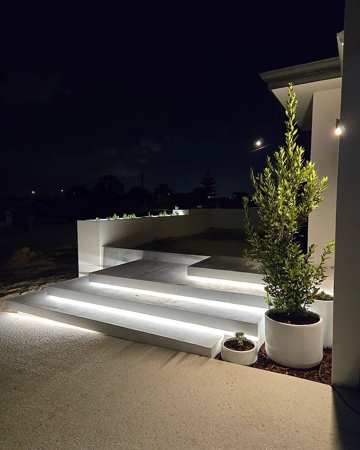 Architectural floating steps to a front entry in architectural white, each tread cantilevered and lit from bel