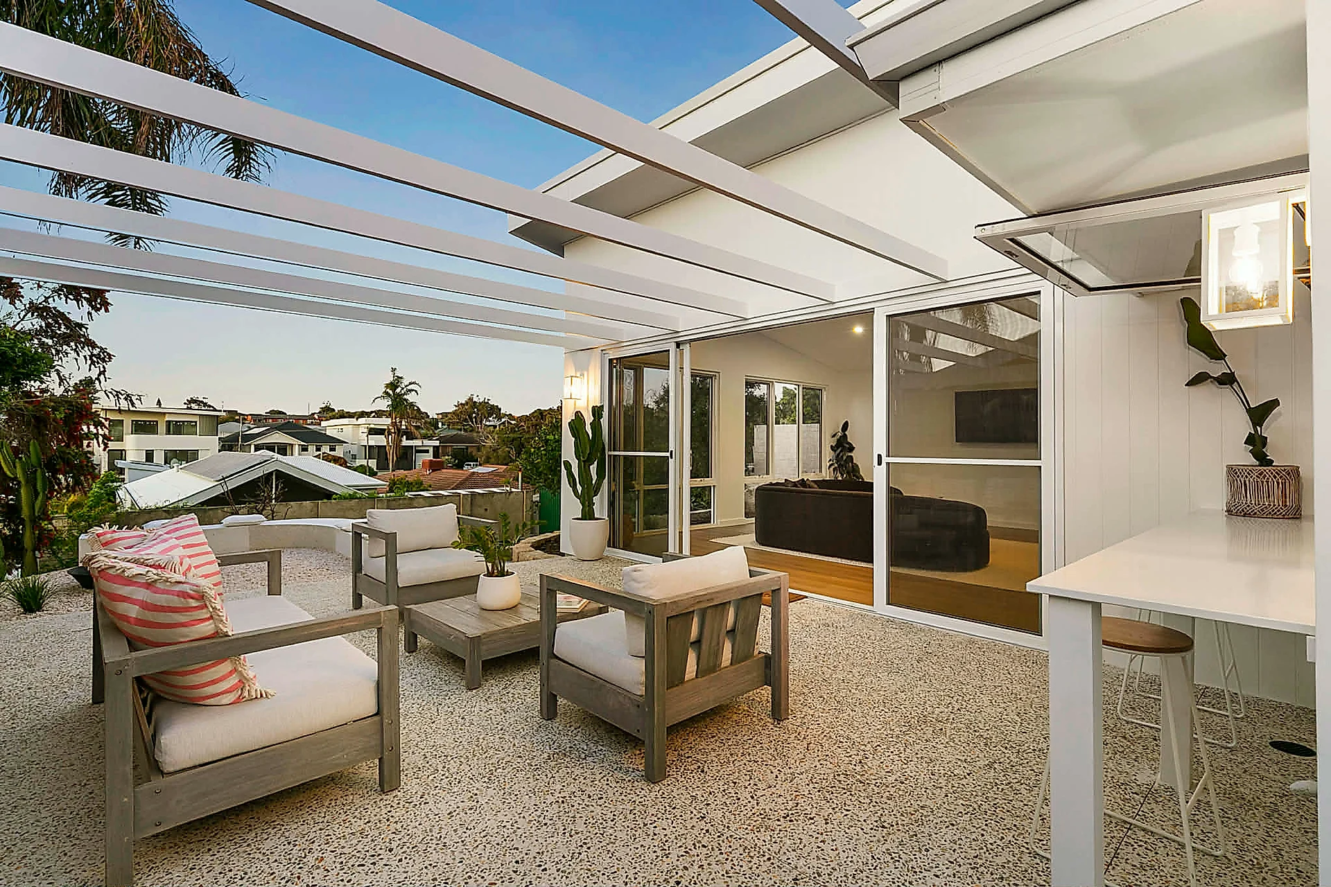 Whole-property renovation. Wattle white exposed aggregate alfresco, honed patio under a white pergola, an off 