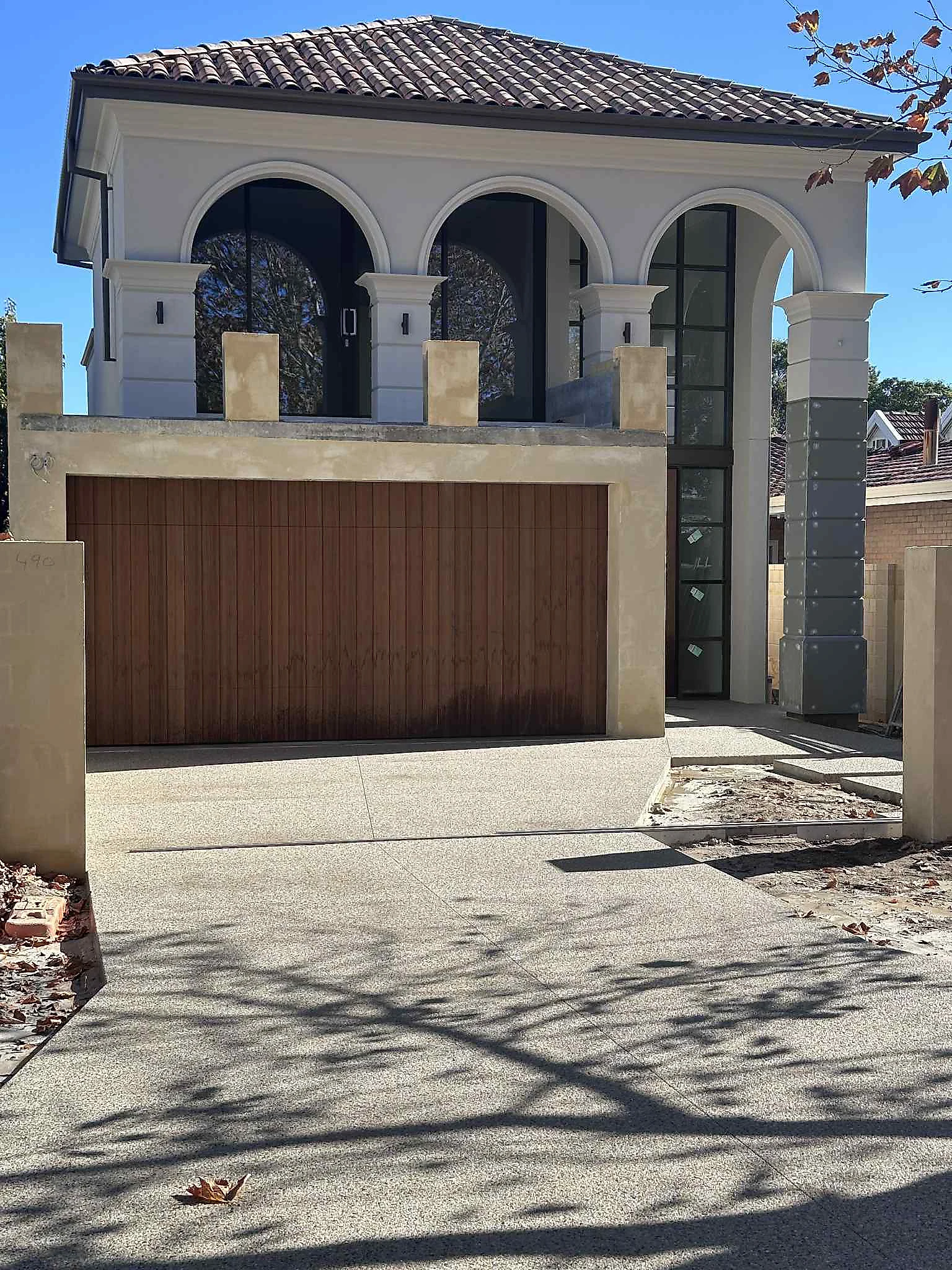 Coral mix driveway and entrance run for an architectural home, warm toned to sit with the render and stonework