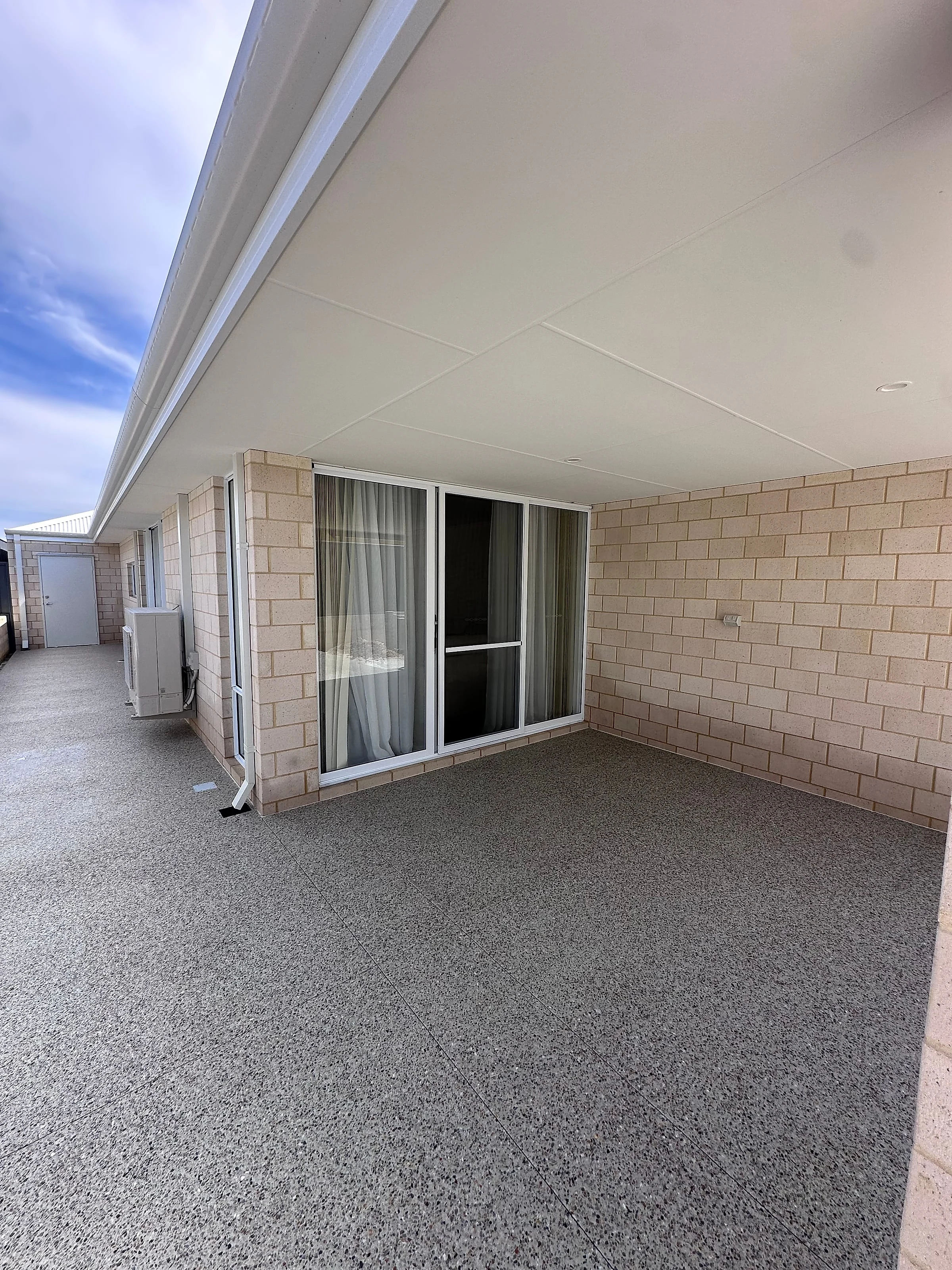 An exposed aggregate alfresco under the main roof, continued out as boundary paths down both sides of the hous