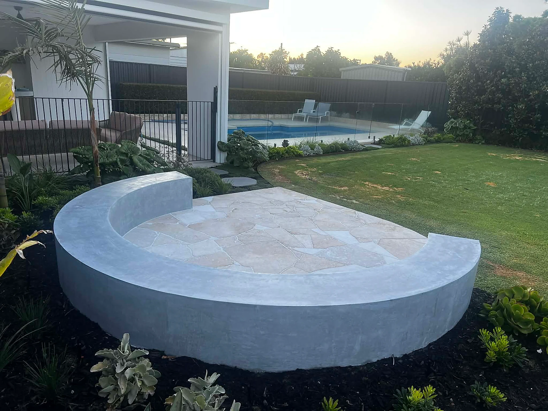 Curved architectural bench seat, fire pit · landscaped backyard