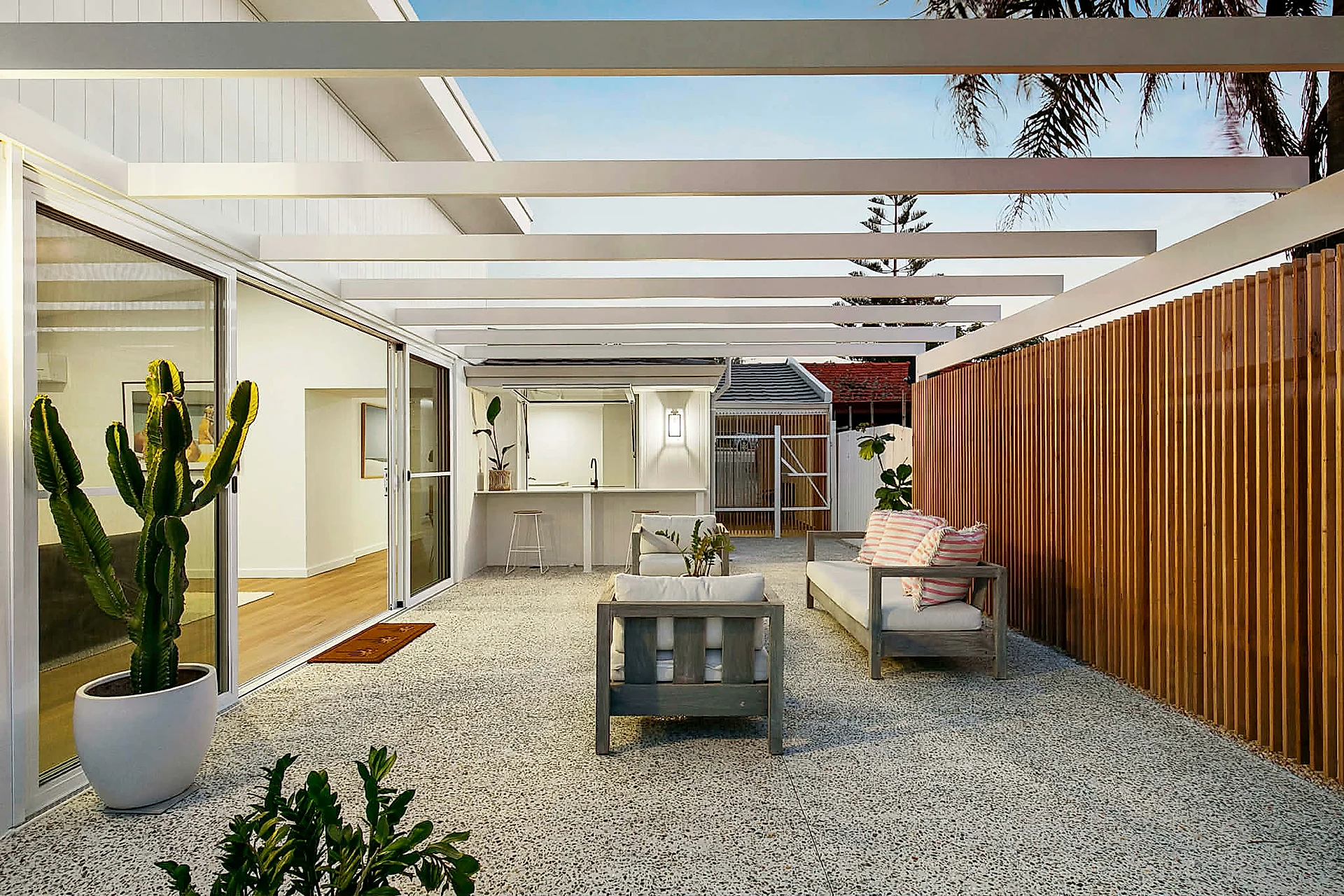 Exposed aggregate alfresco under a white pergola · North Beach